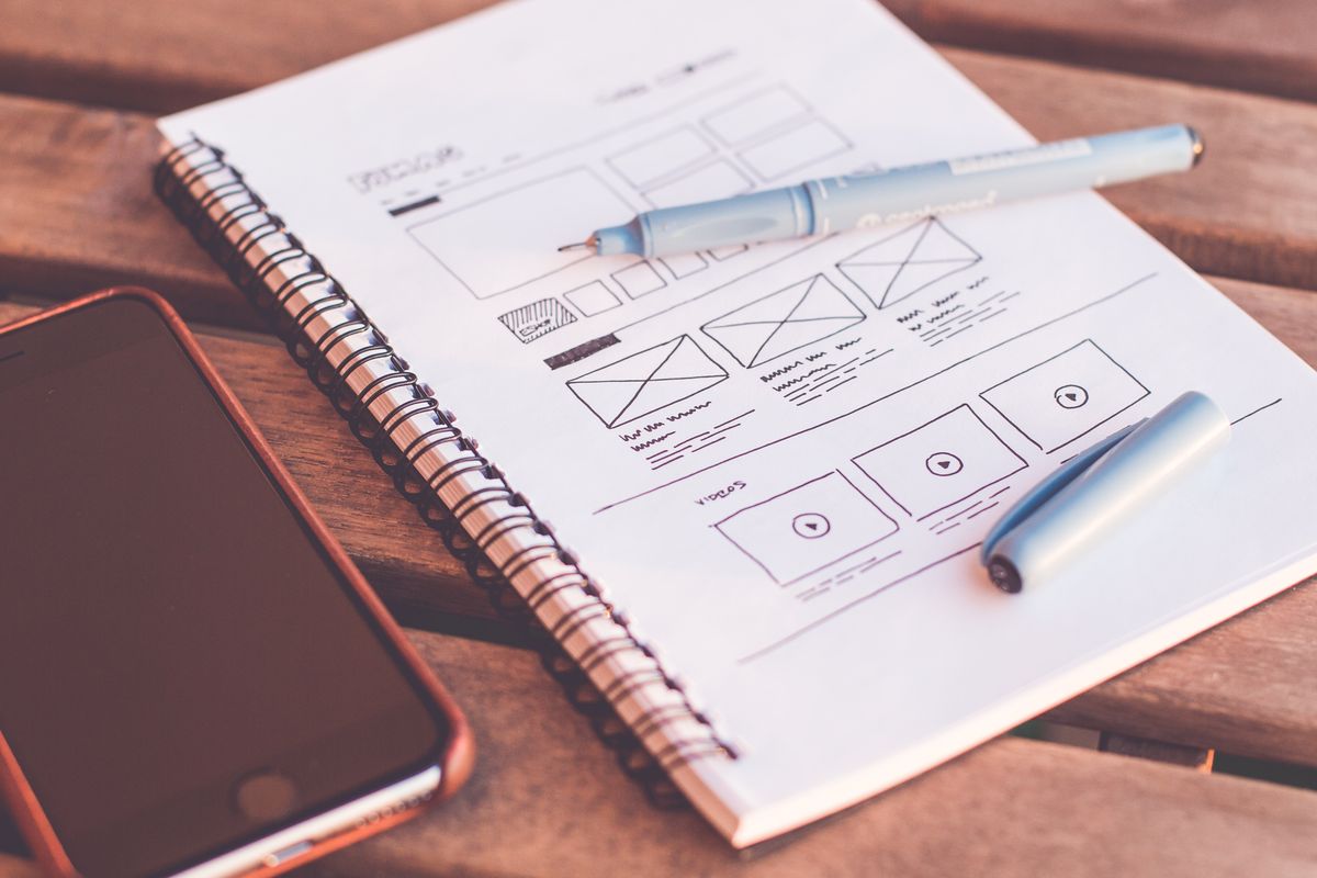 Designer working on a website layout and user interface mockups on a laptop